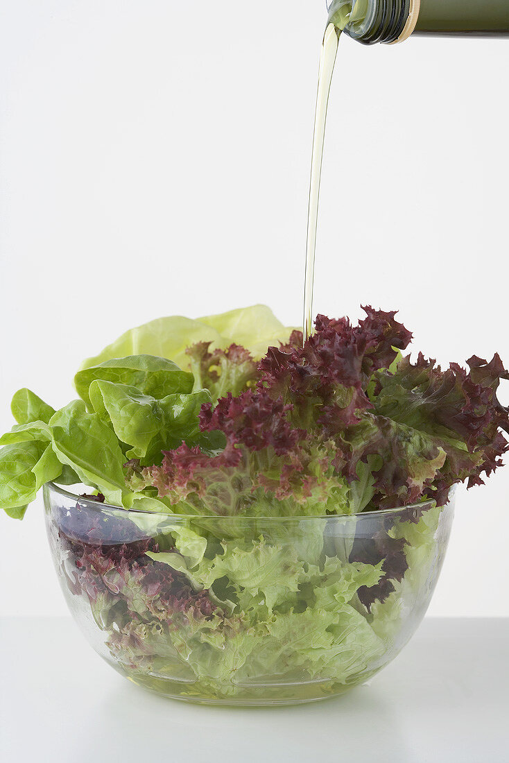 Pouring oil onto mixed salad leaves