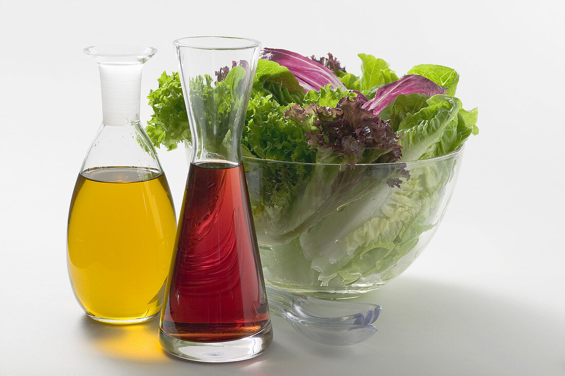 Oil and vinegar in carafes in front of salad bowl