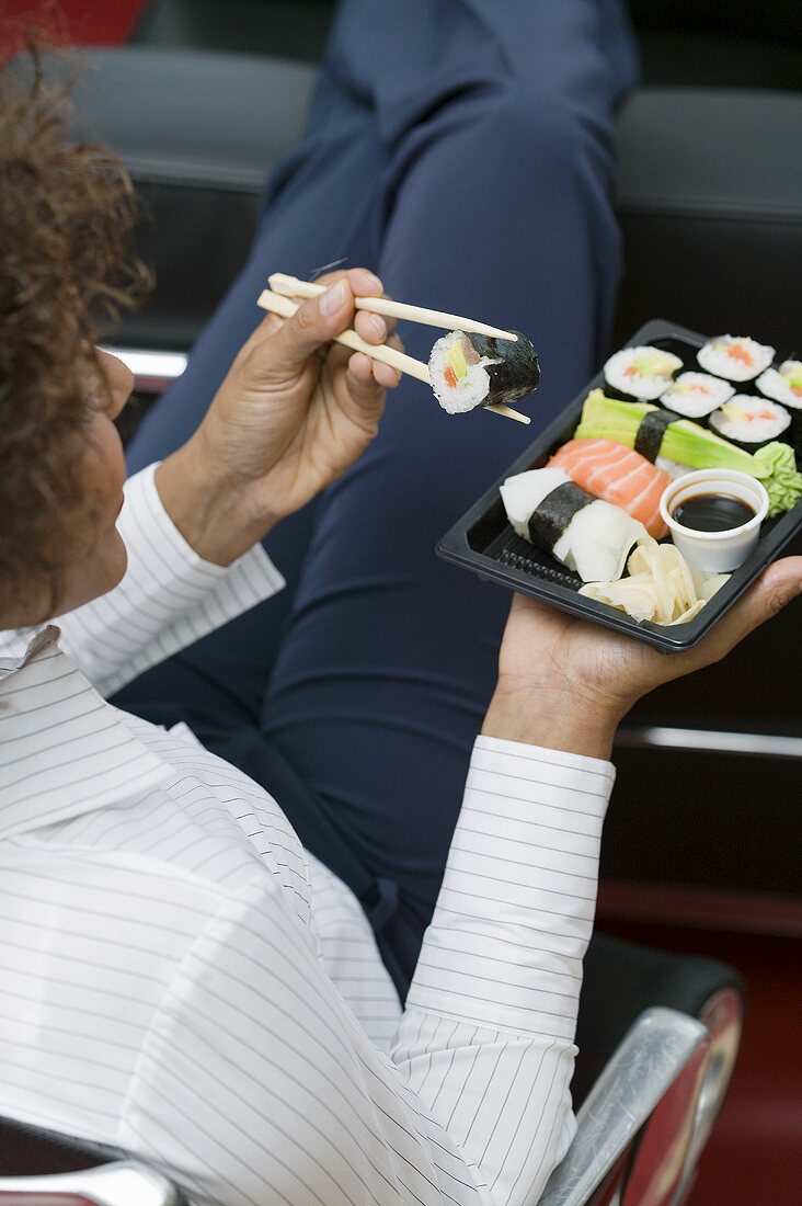 Frau isst Sushi im Büro