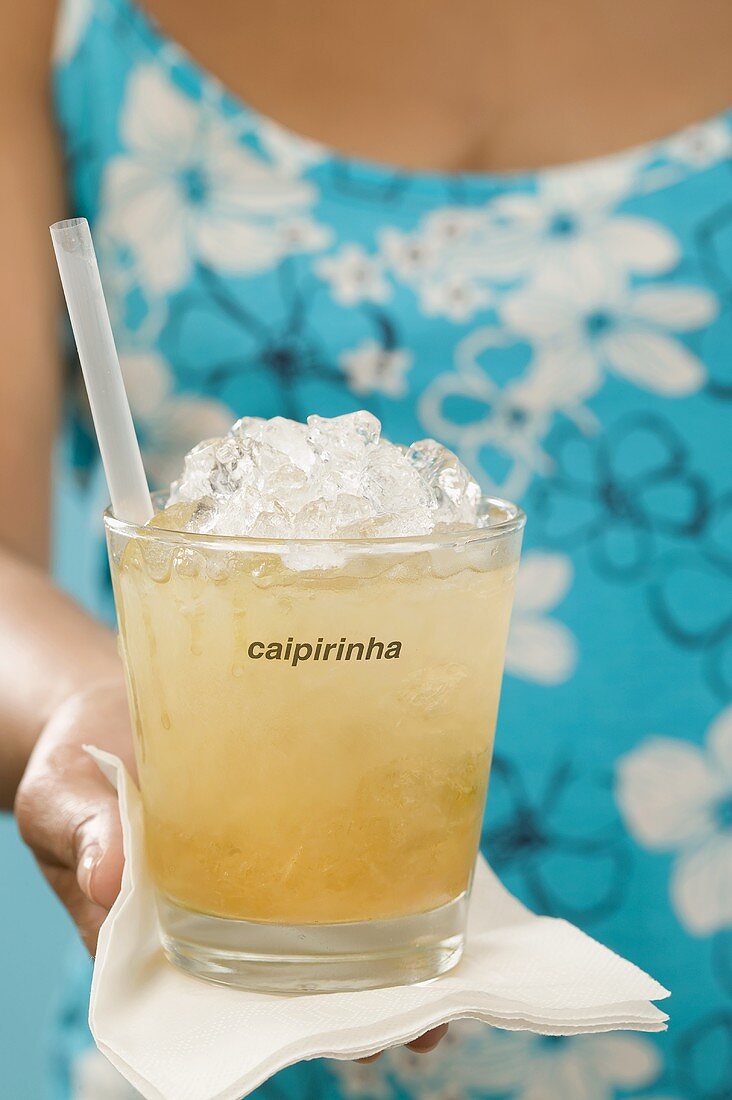 Frau hält Cocktail im Glas mit Aufschrift Caipirinha