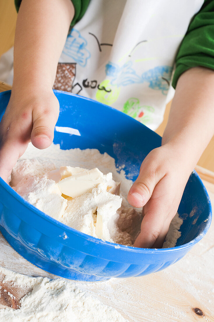 Kind vermischt Mehl mit Butter in Schüssel