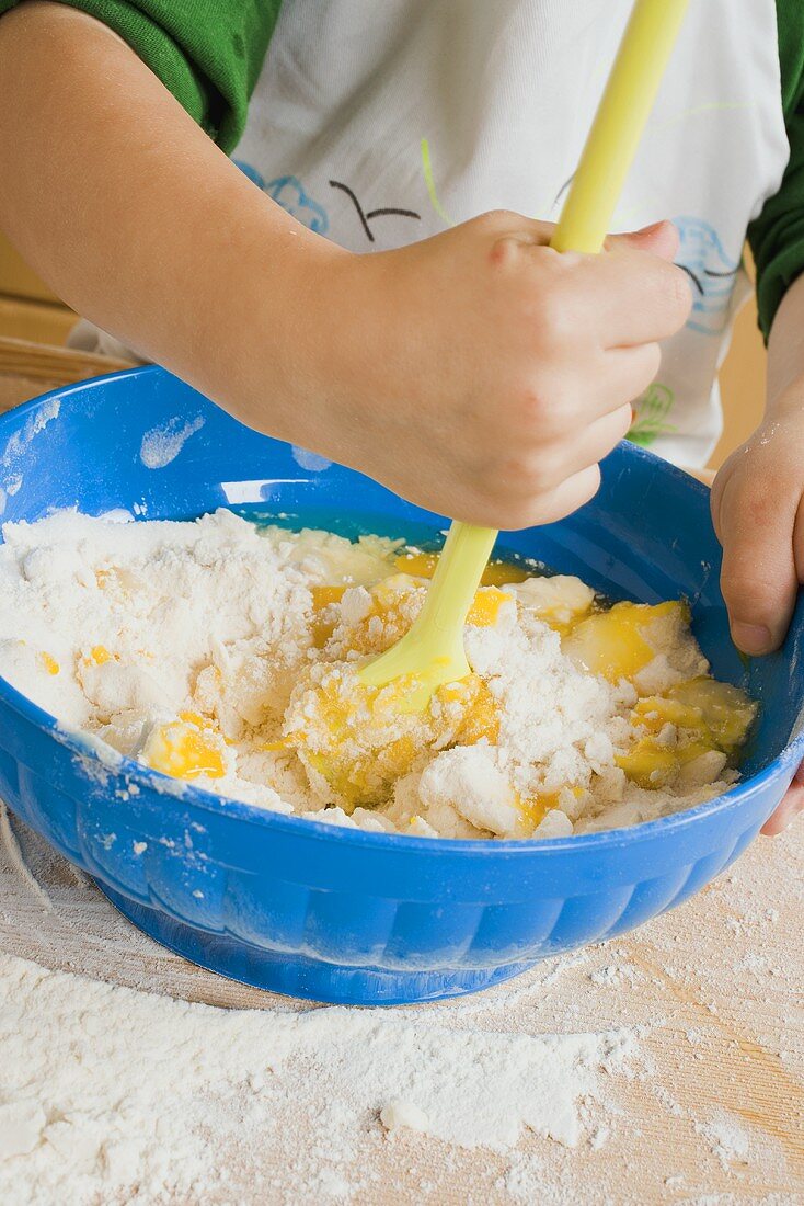 Kind verrührt Ei mit Mehl und Butter in Schüssel