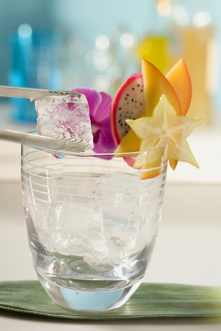 Putting ice cubes into a cocktail glass