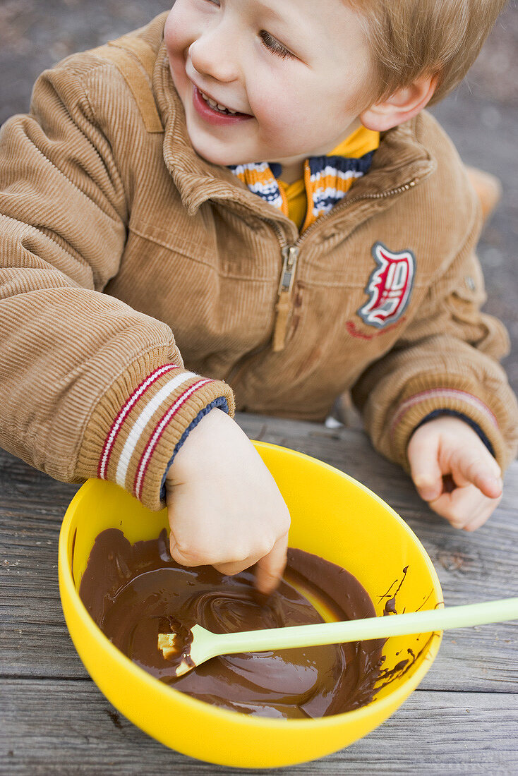 Kind nascht Schokoladensauce aus Schüssel