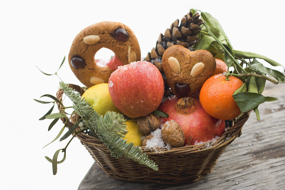 Lebkuchen mit Obst, Nüssen und Zapfen im Korb