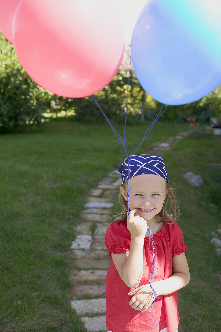 Kleines Mädchen mit Luftballons im Garten