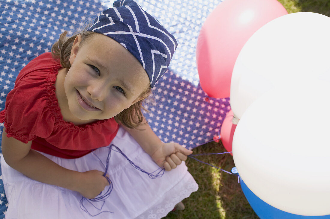 Kleines Mädchen hält Luftballons im Garten am 4th of July