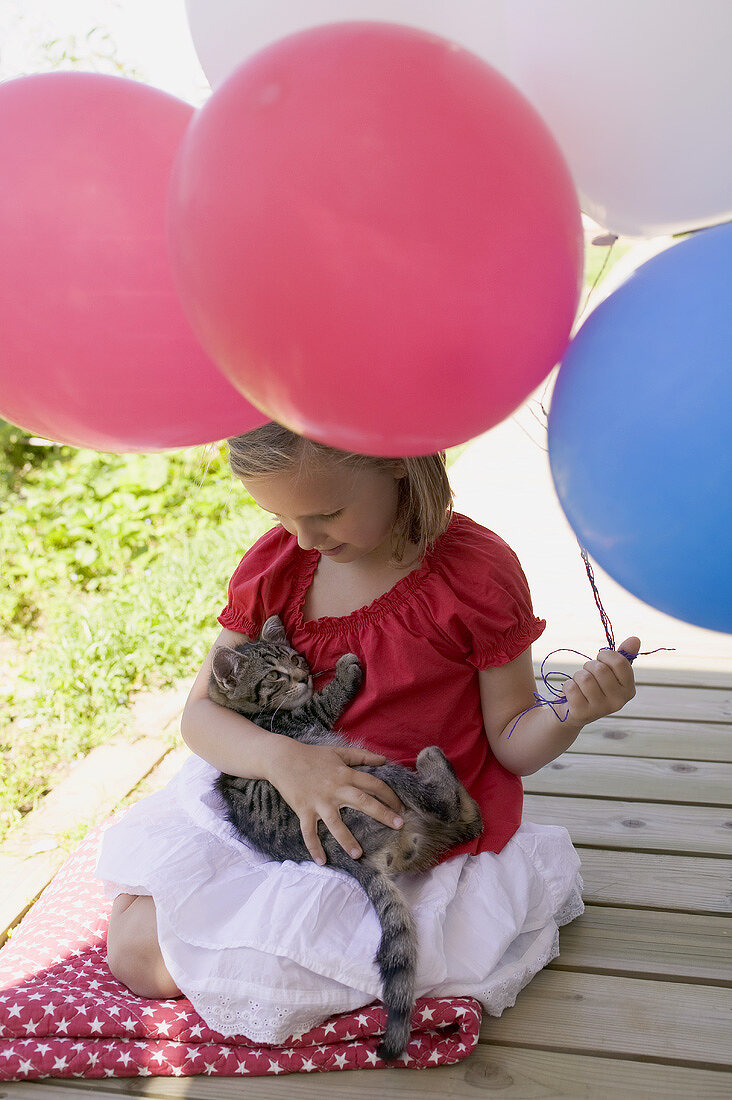 Kleines Mädchen hält Katze und Luftballons (4th of July, USA)