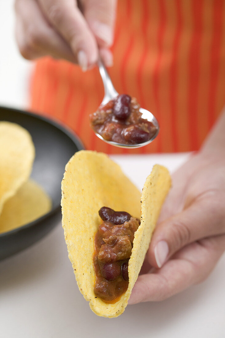 Filling tacos with chili con carne