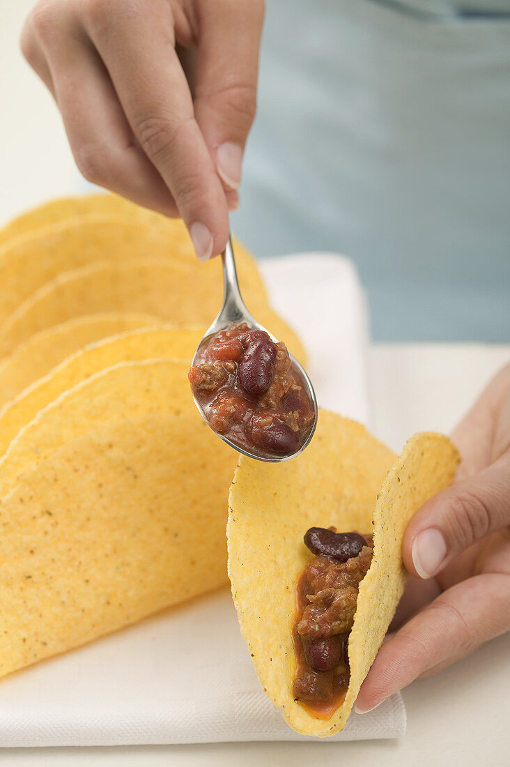Filling tacos with chili con carne