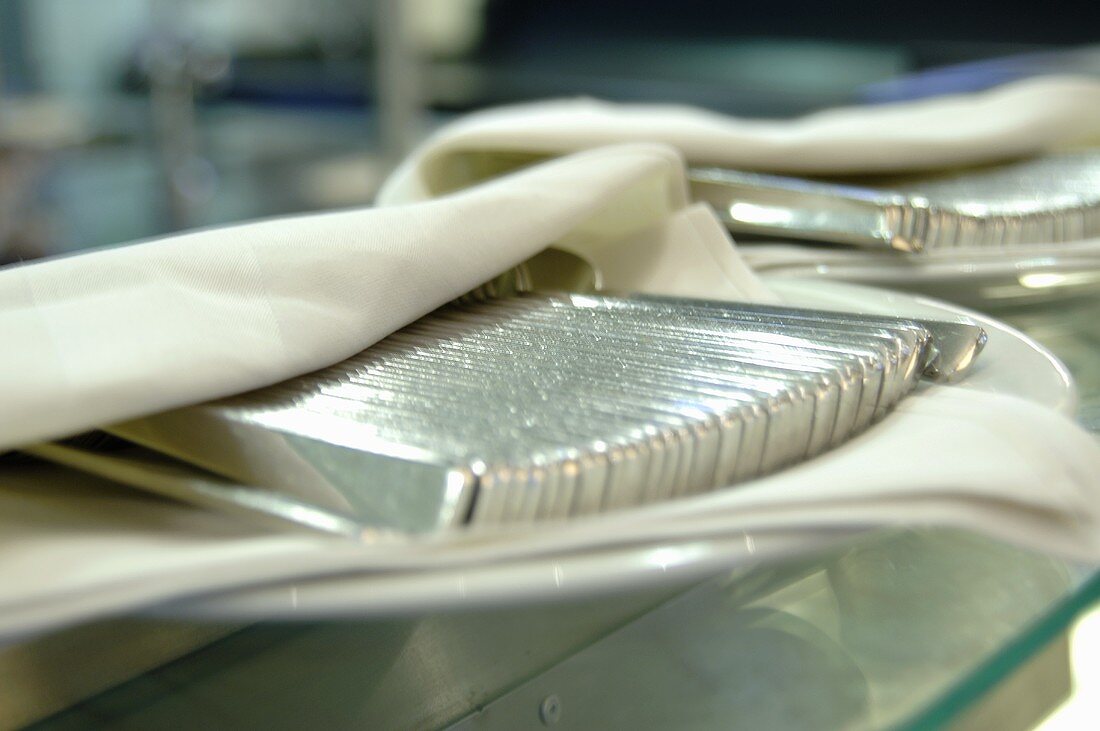 Hotelbesteck, mit Serviette bedeckt, auf Teller in Grossküche