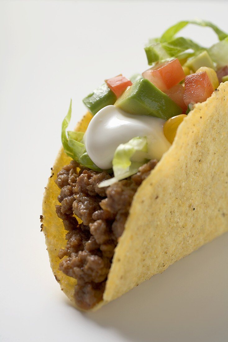 Taco filled with mince, lettuce, avocado and sour cream