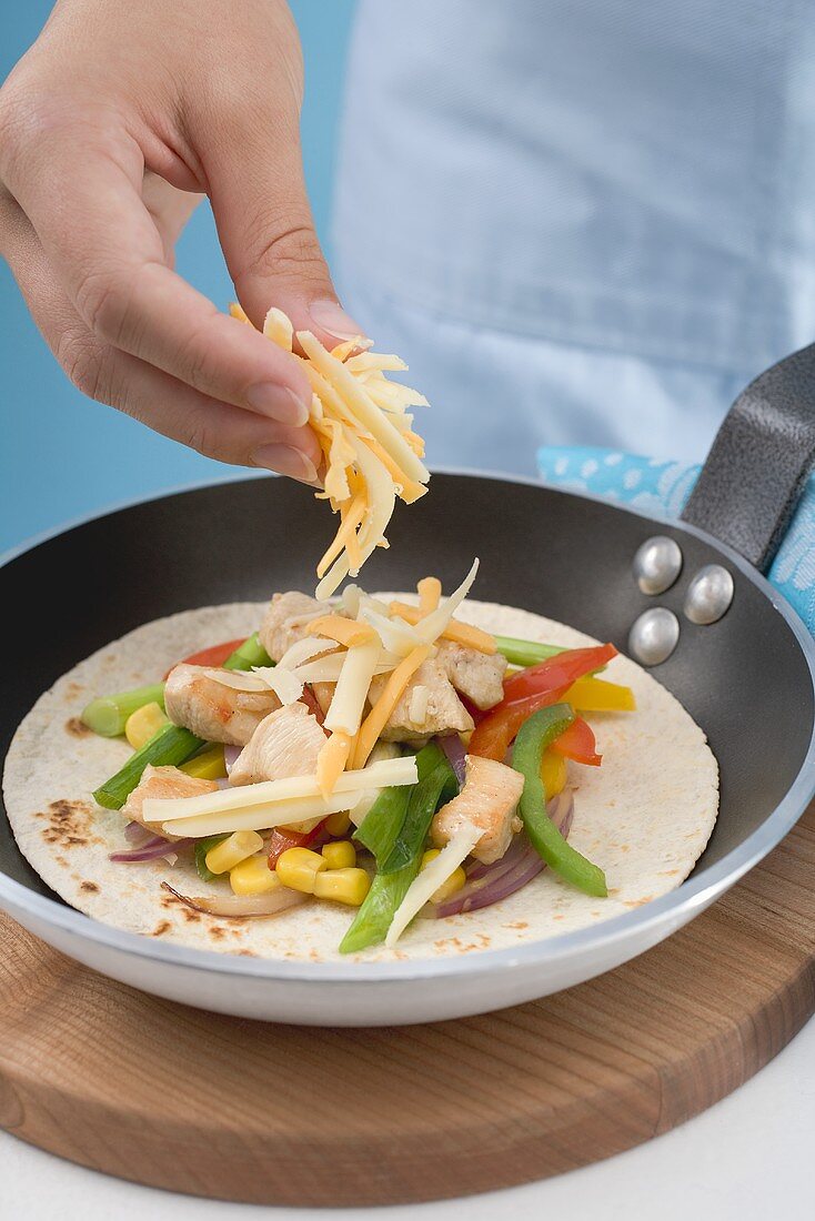 Hand streut geriebenen Käse auf Fajita