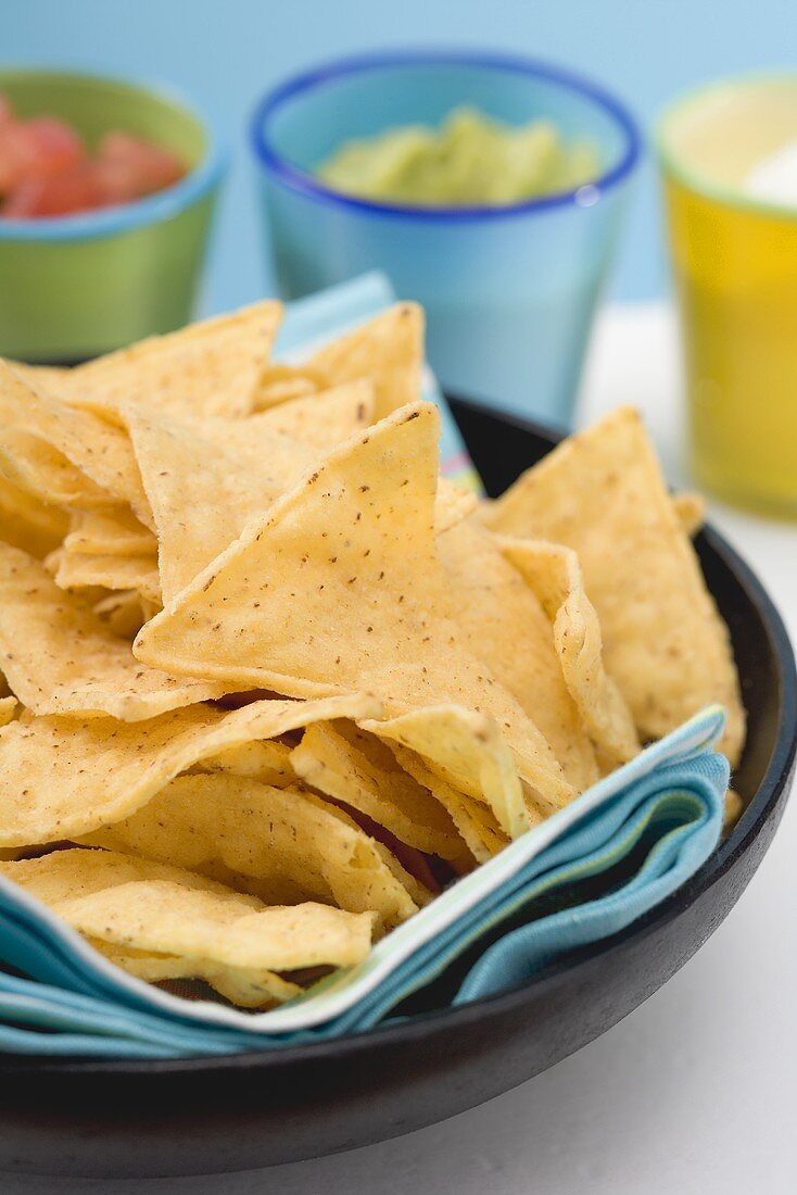 Nachos in dish, dips in background