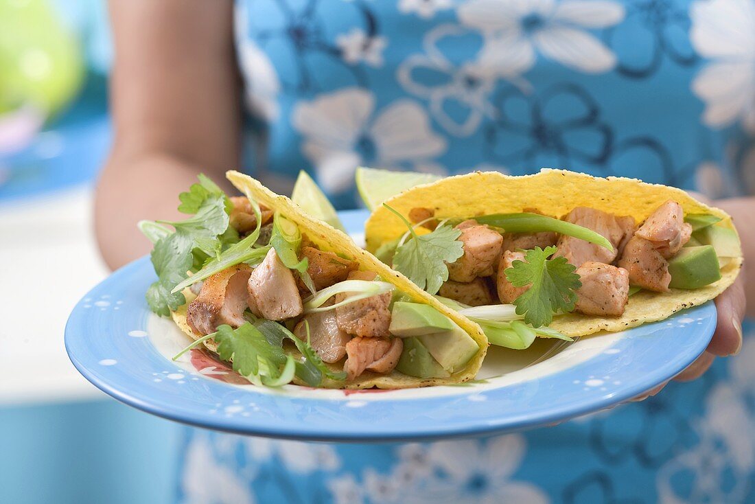 Frau hält Teller mit zwei Tacos