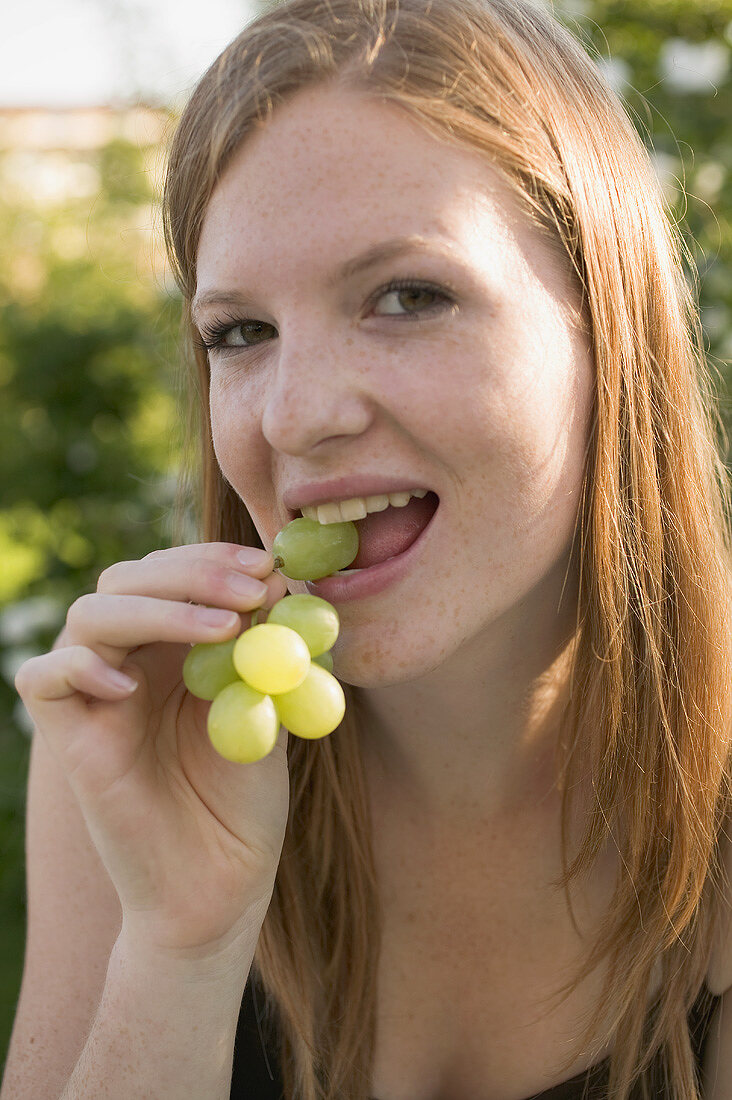 Woman eating green grapes out of doors