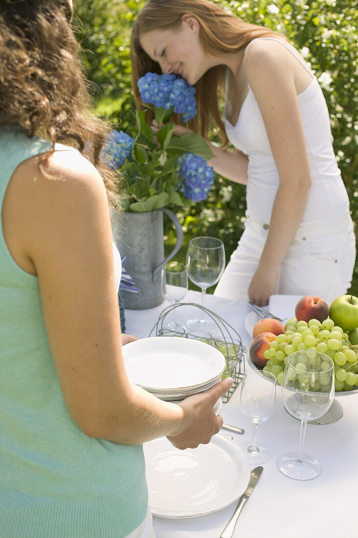 Zwei Frauen decken den Tisch für eine Gartenparty