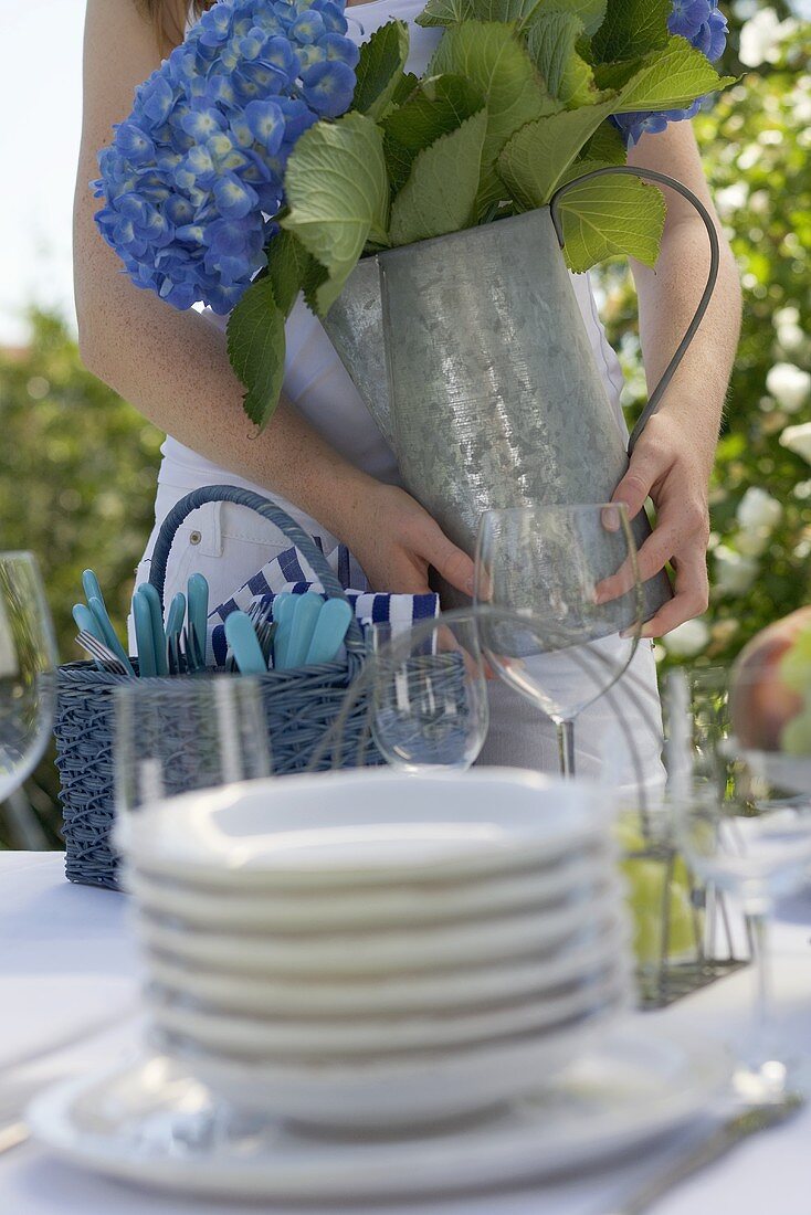 Woman decorating laid table with vase of flowers