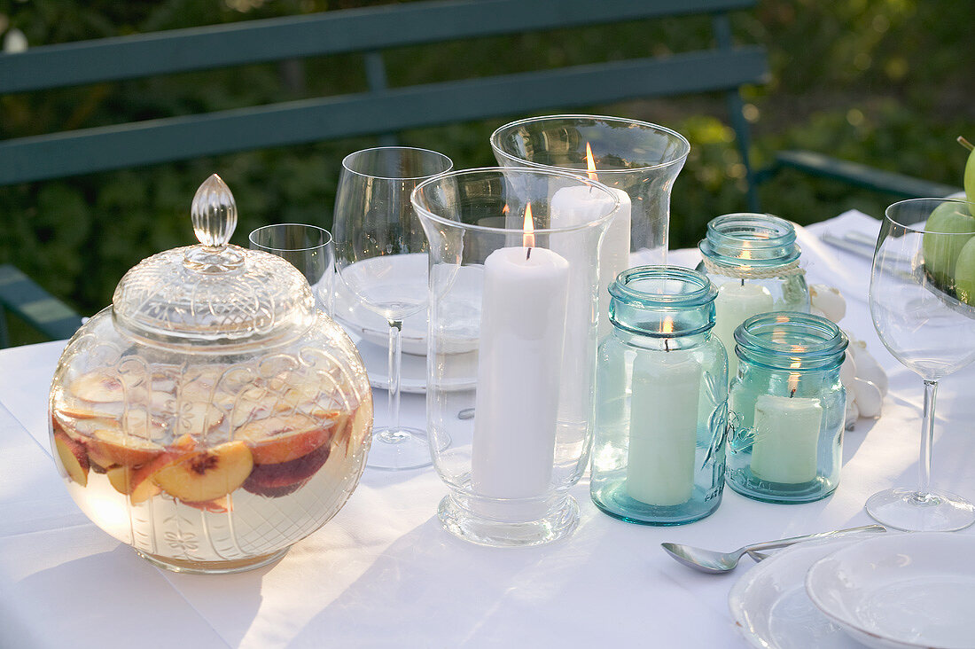 Pfirsichbowle, Windlichter und Gläser auf Tisch im Garten