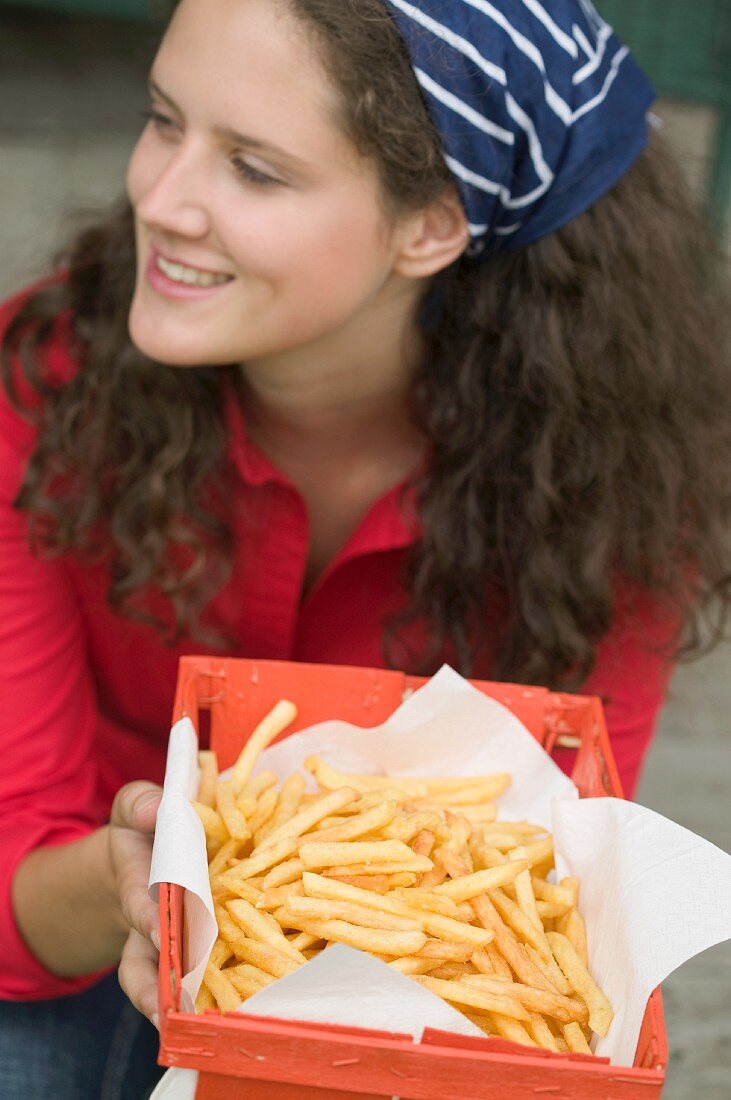 Frau hält Korb mit Pommes frites