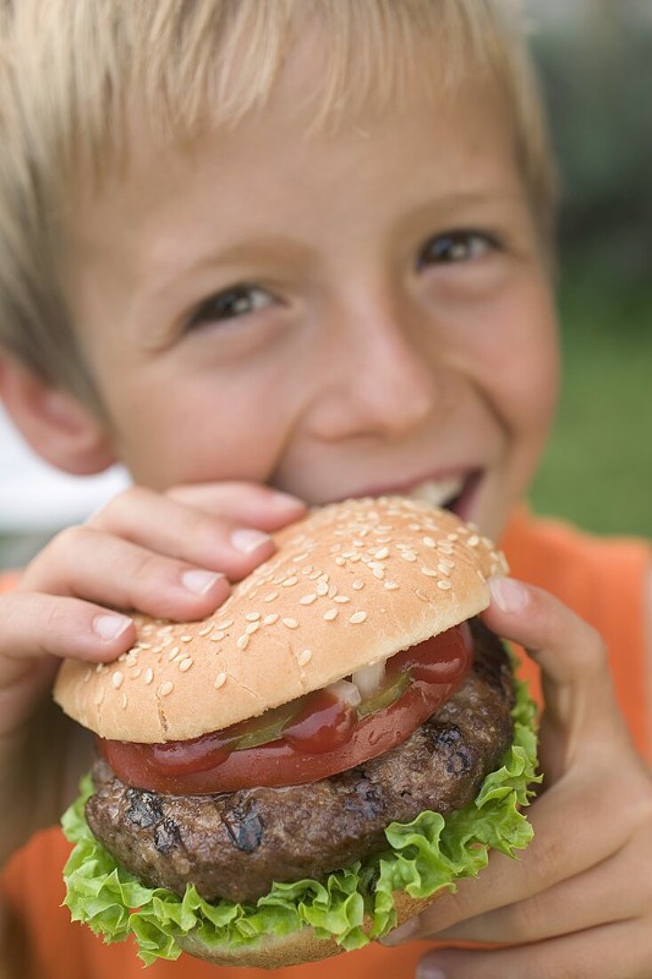 Small boy eating hamburger