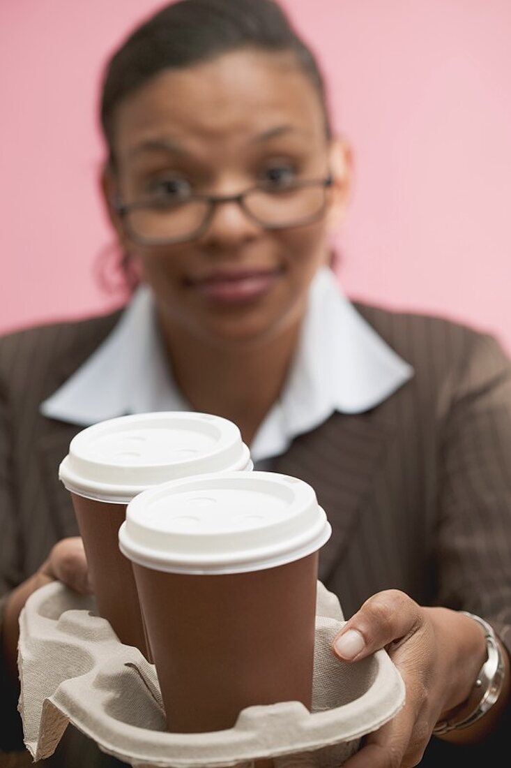 Geschäftsfrau bietet zwei Kaffeebecher an