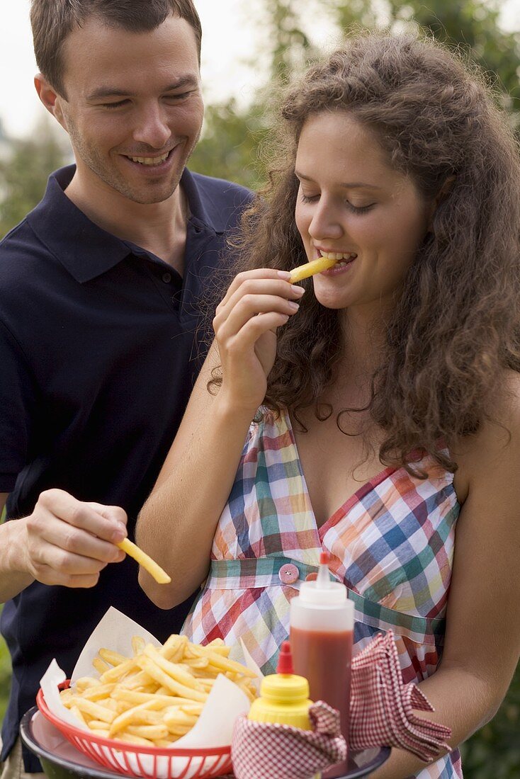 Paar isst Pommes frites beim Grillfest