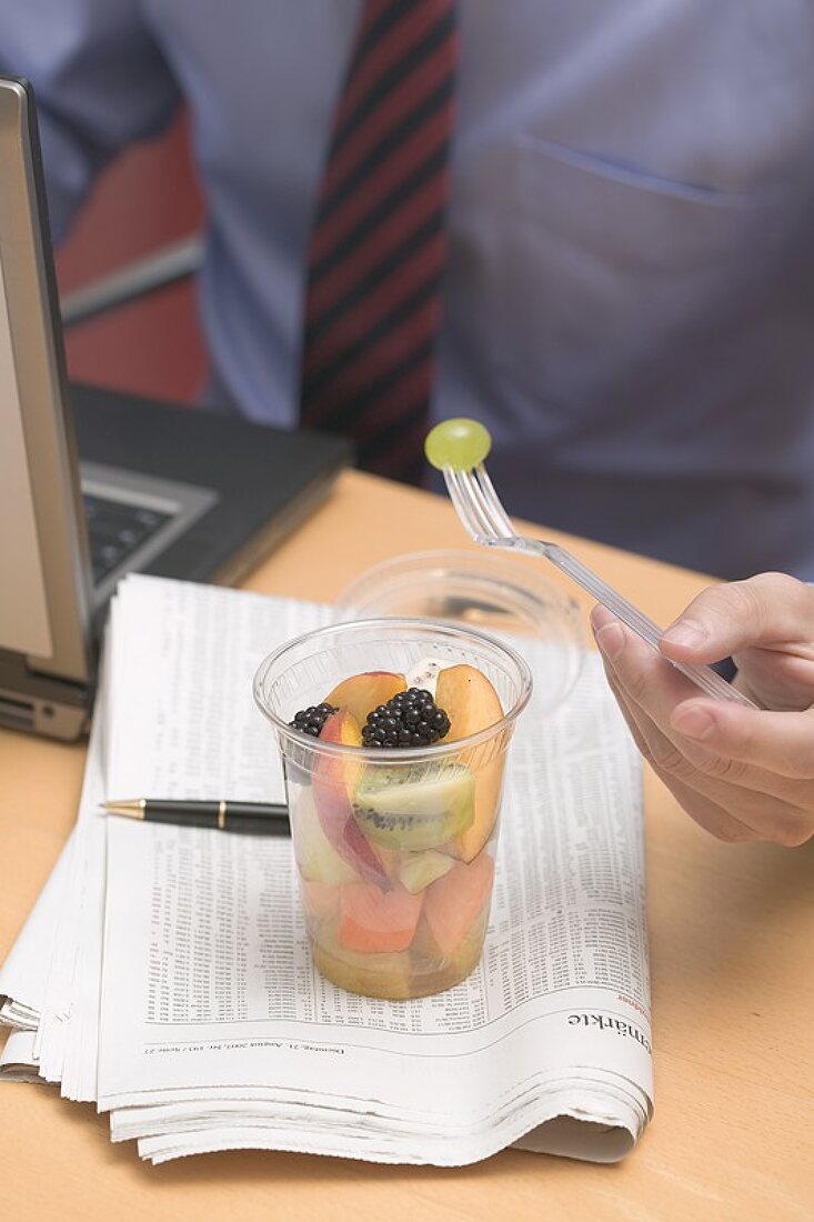 Businessman eating fruit salad in office