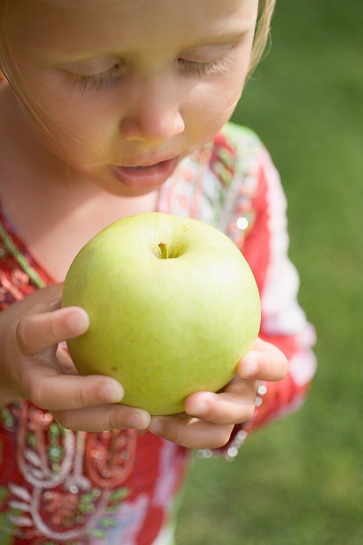 Kleines Mädchen hält grossen grünen Apfel
