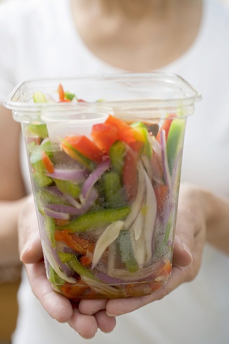 Frau hält Plastikschale mit Gemüse