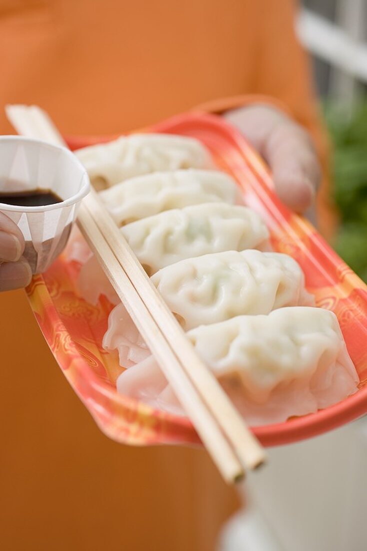 Woman holding wontons on plastic tray