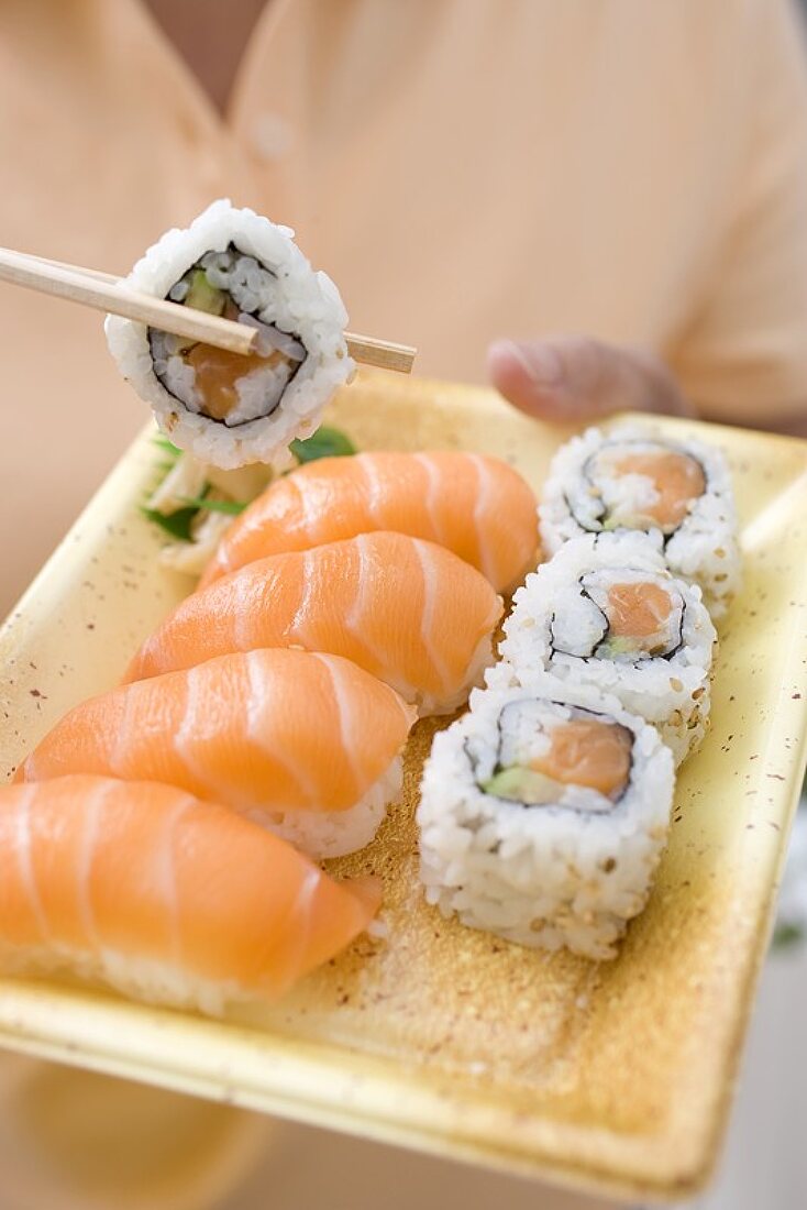 Frau hält Plastikschale mit Sushi