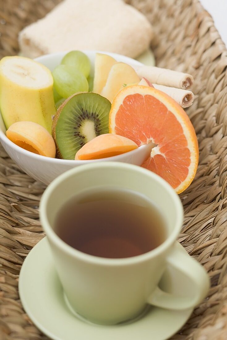 Cup of tea, fresh fruit and towel in basket