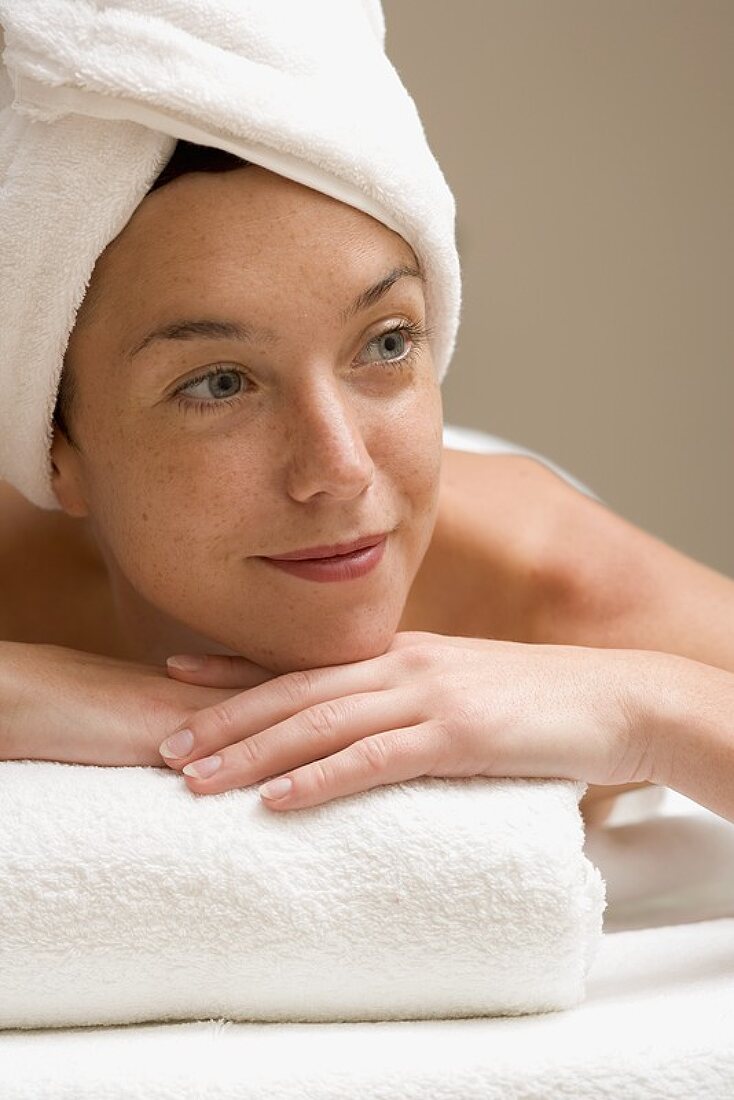 Woman lying down, resting on white towel