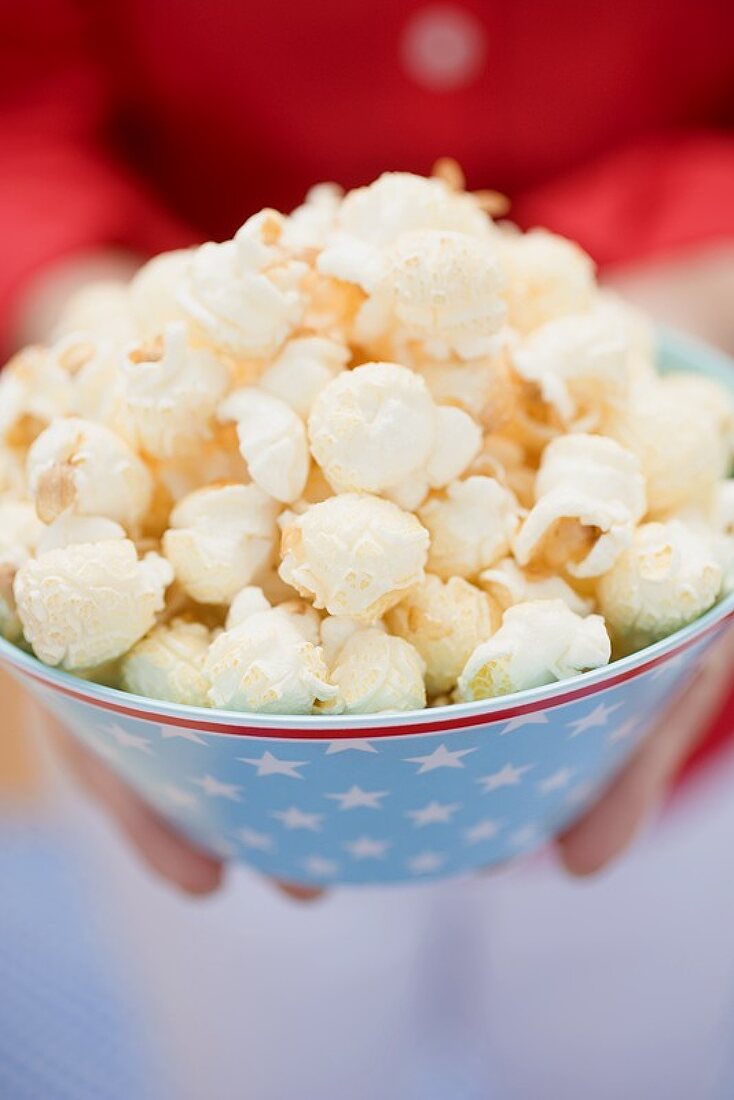 Woman holding popcorn in bowl with stars (4th of July, USA)