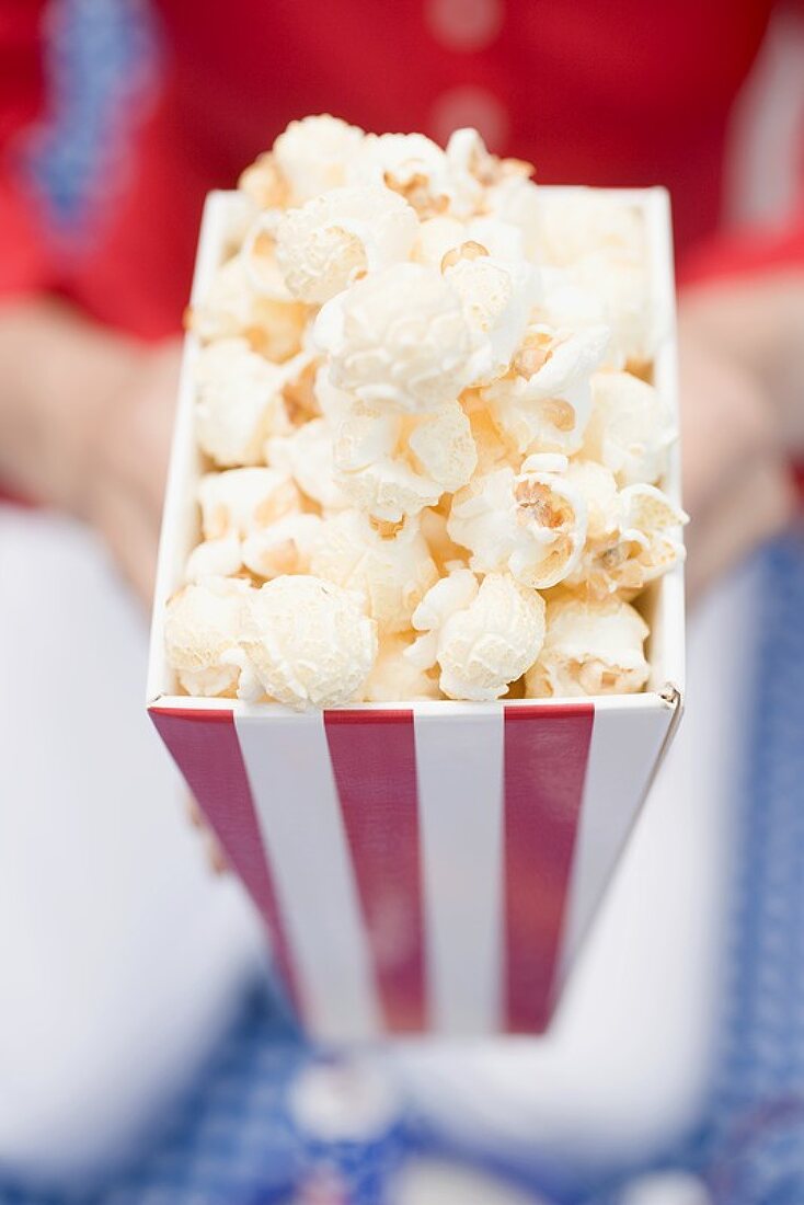 Frau hält Popcorn in gestreifter Tüte (4th of July, USA)