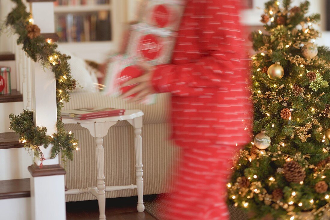 Frau trägt Schachteln mit Weihnachtsschmuck durch Wohnzimmer