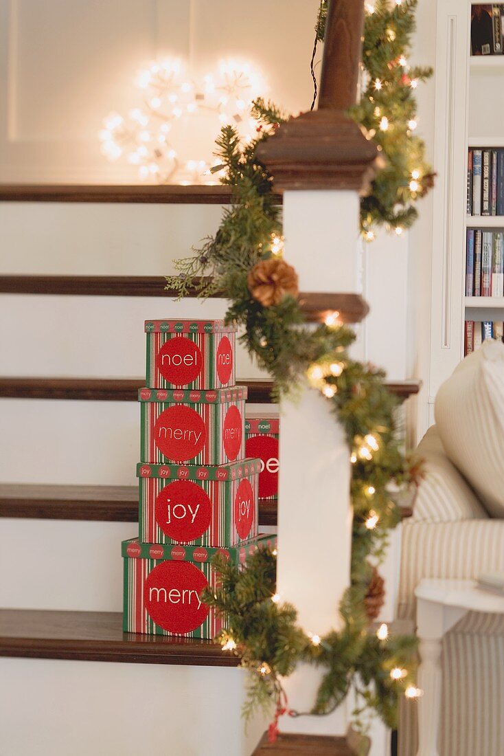 Schachteln mit Weihnachtsdeko und Tannengirlande auf Treppe