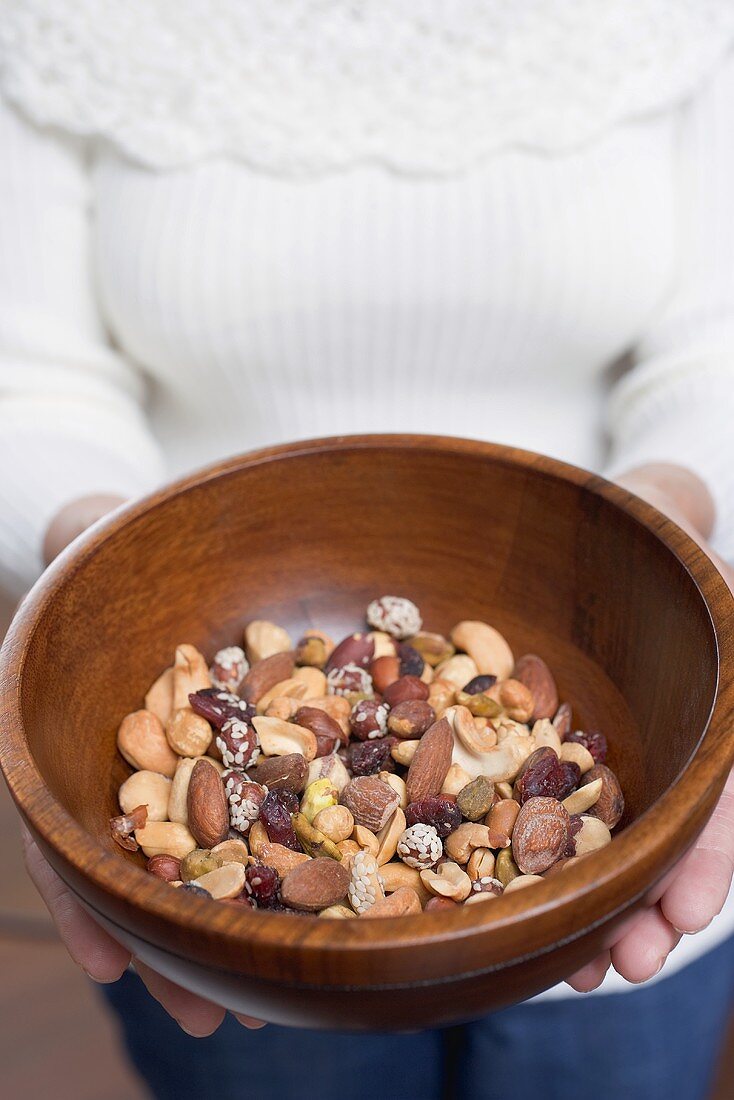Woman holding wooden bowl of assorted nuts