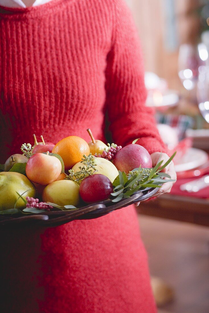 Frau hält Obstschale (weihnachtlich)