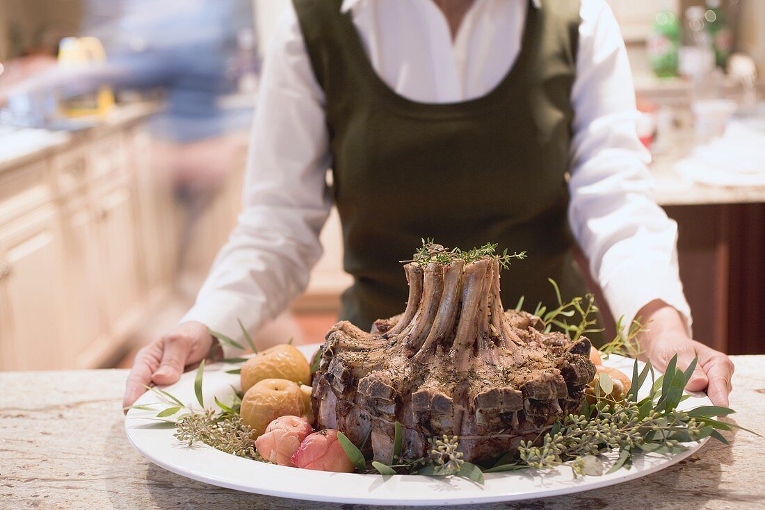 Frau mit festlichem Kronenbraten in der Küche