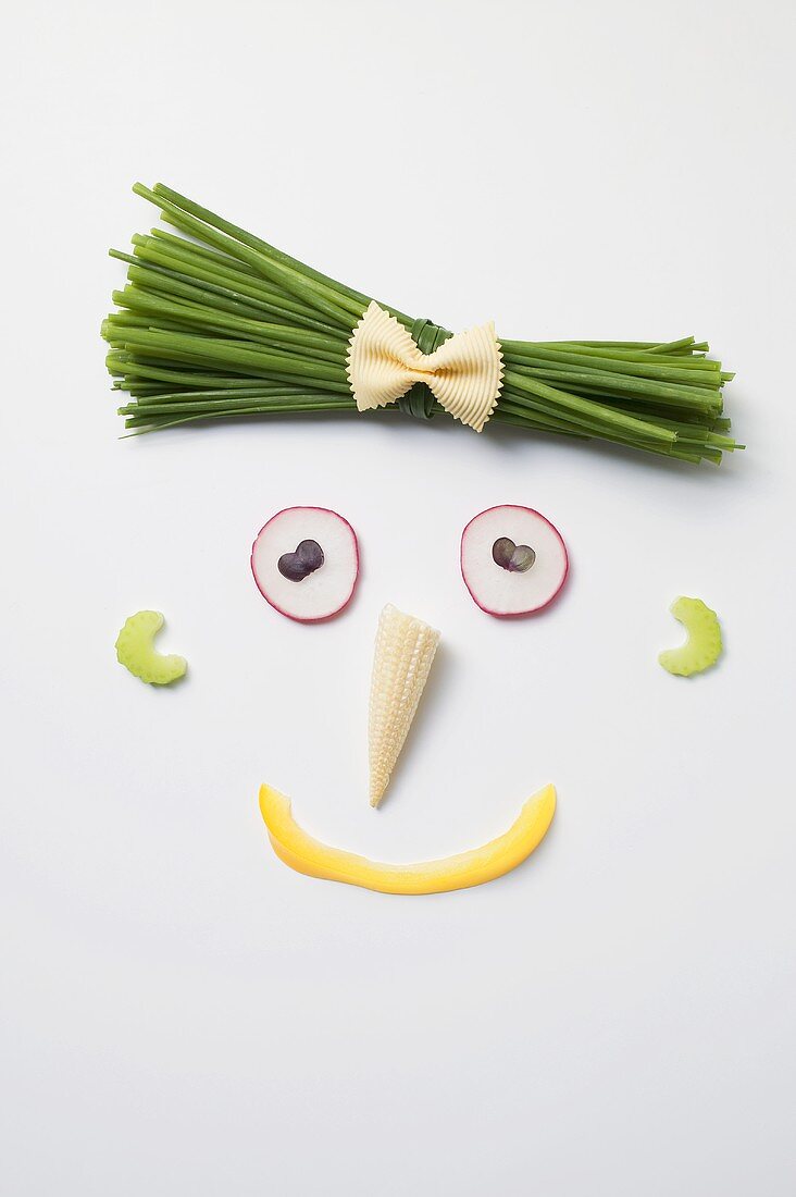 Lustiges Gesicht aus Gemüse, Maiskölbchen und Schnittlauch