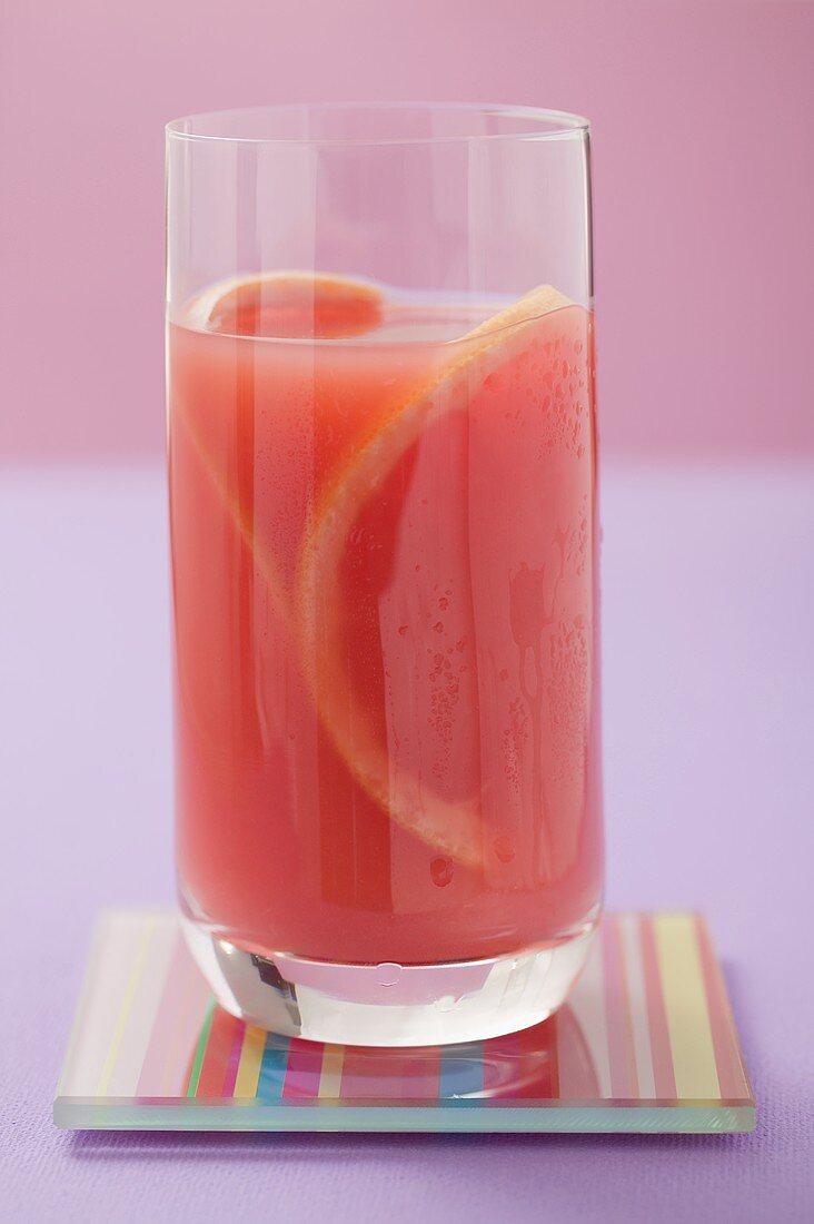 Glas rosa Grapefruitsaft mit Grapefruitscheiben
