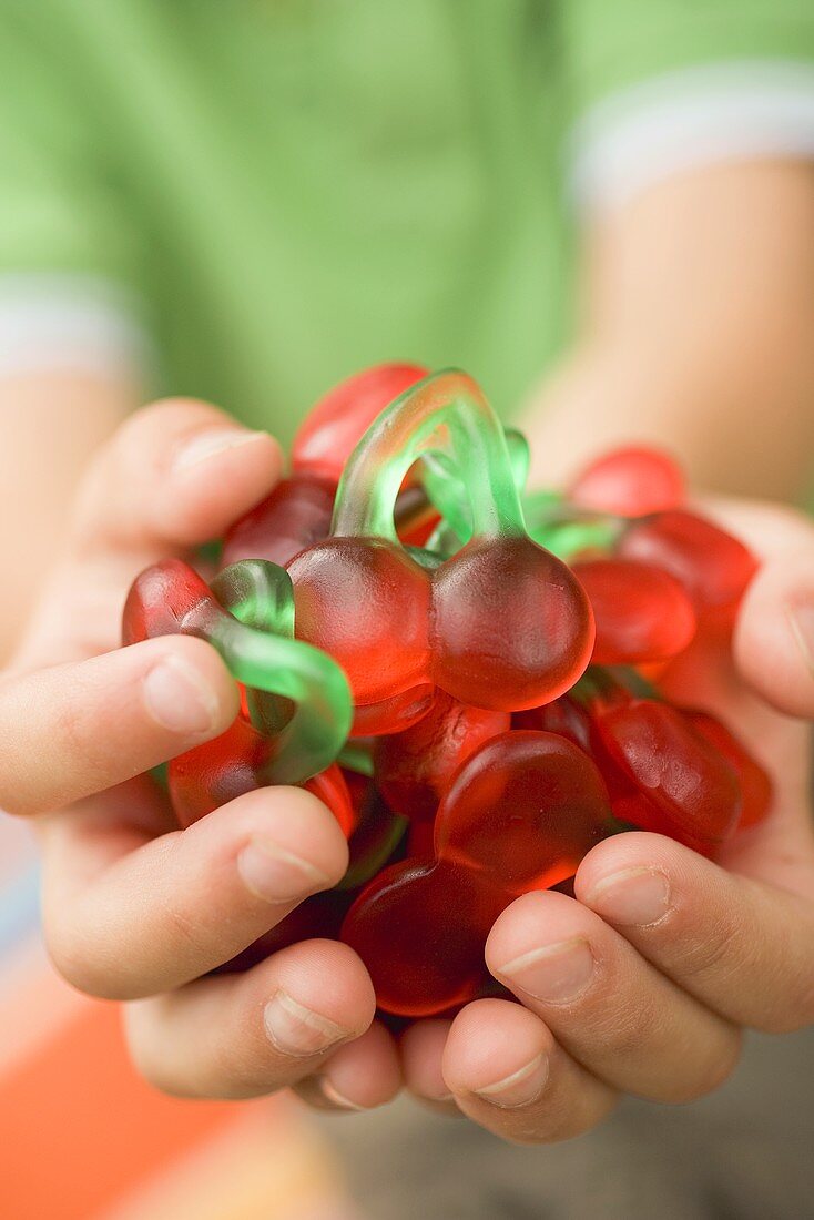 Child's hands holding cherry jelly sweets
