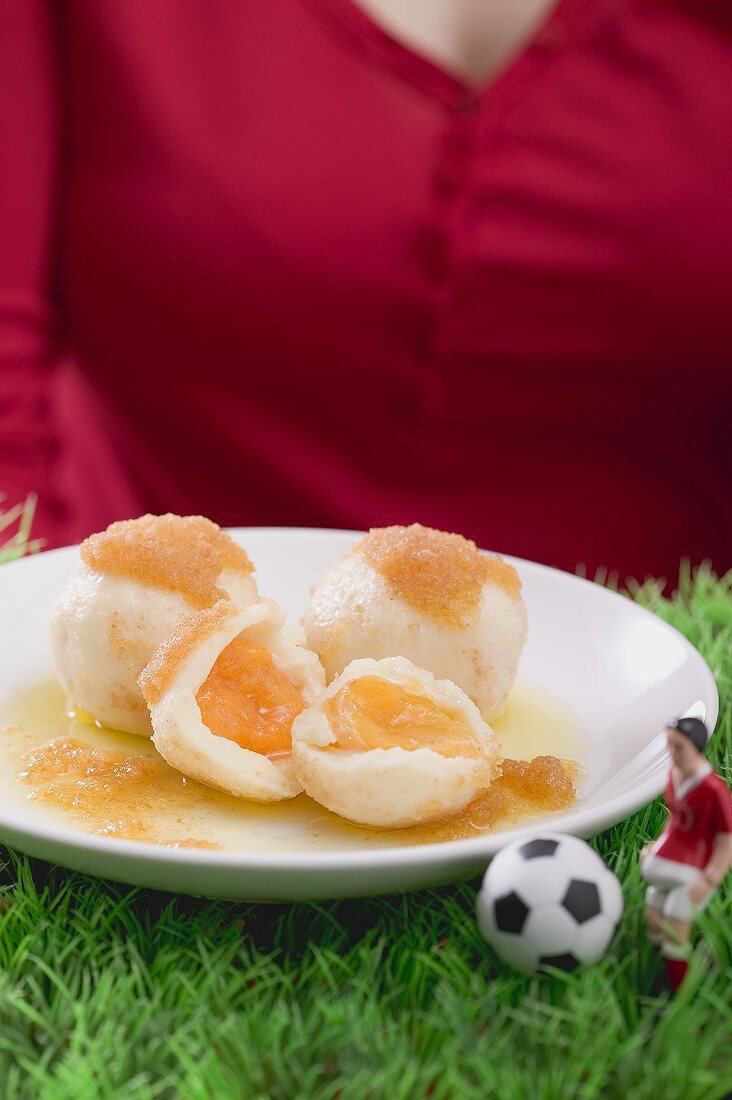 Woman serving apricot dumplings with football figure & football