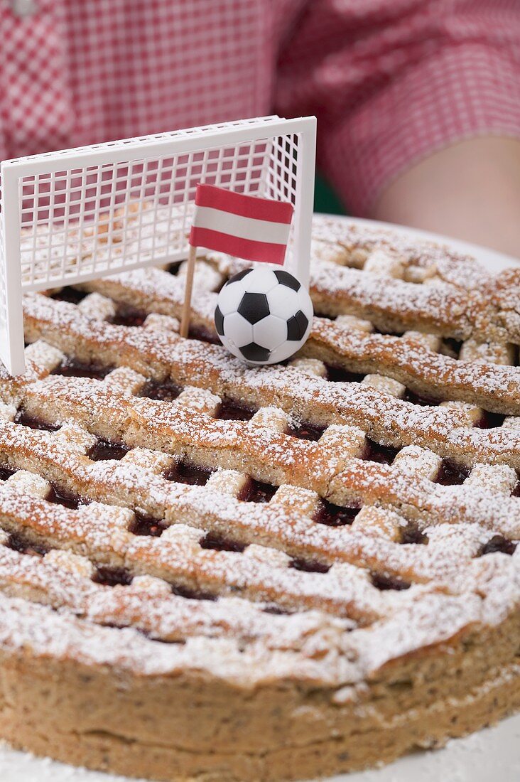 Frau hält Linzertorte mit Fussballdeko und Österreich-Flagge