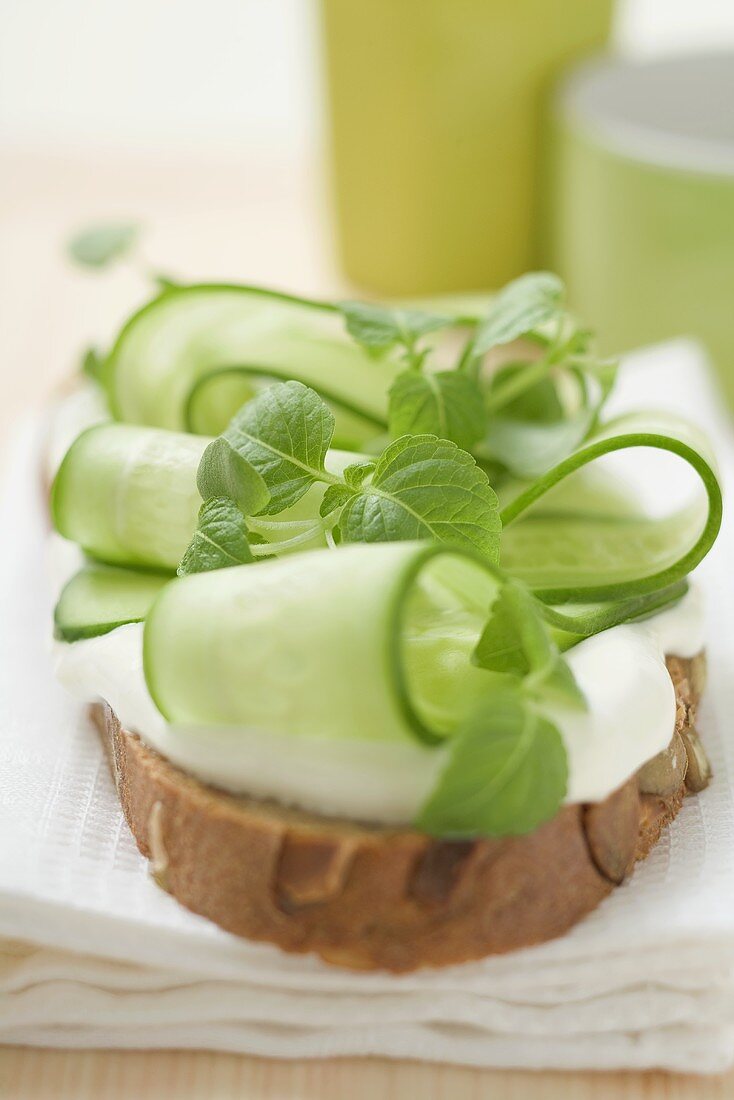 Belegtes Brot mit Joghurt, Gurkenscheiben und Kräutern