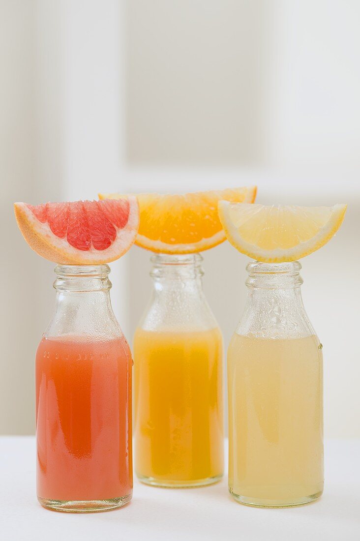 Drei Fruchtsäfte in Flaschen mit frischen Fruchtschnitzen