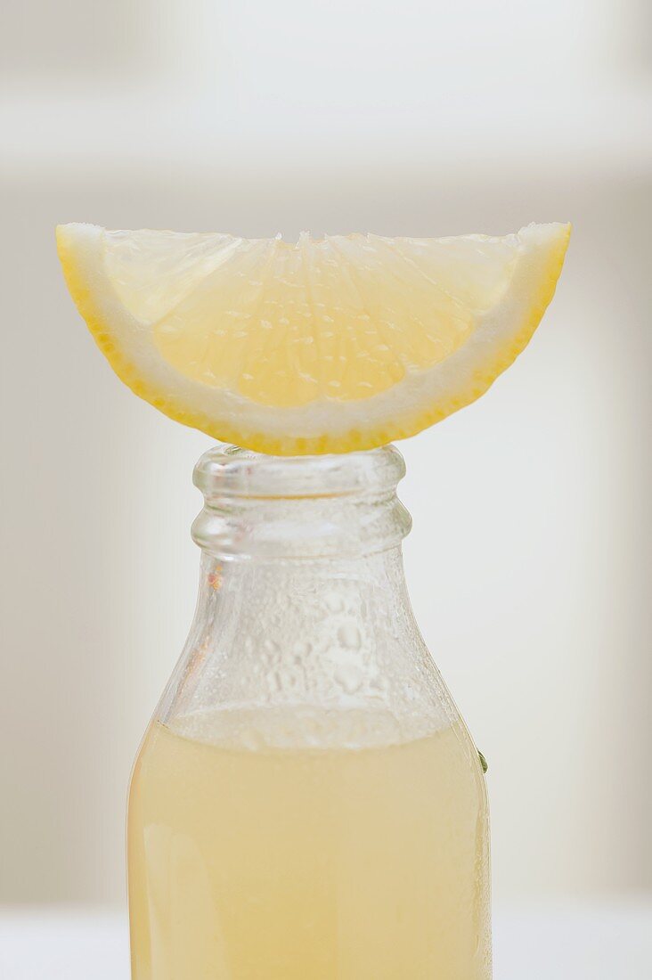 Lemon juice in bottle with fresh lemon wedge