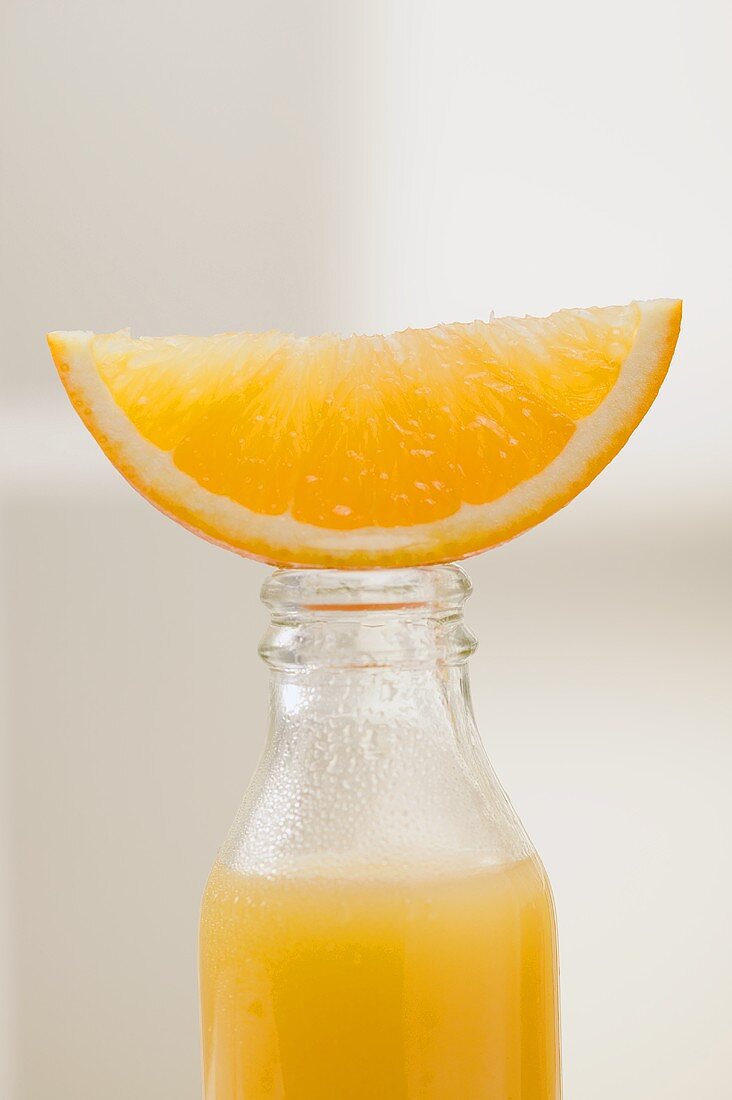 Orange juice in bottle with fresh orange wedge